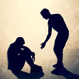 Una persona tiende la mano a otra que está sentada en el piso